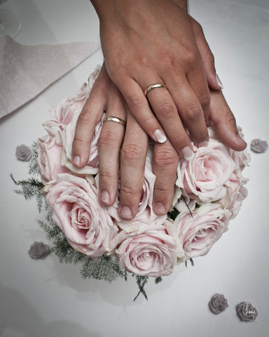 Hands of newlyweds on pink bouquet