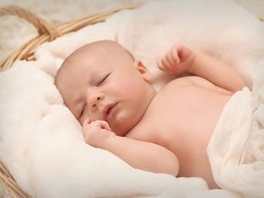 A baby sleeping comfortably in a basket with towels and blankets