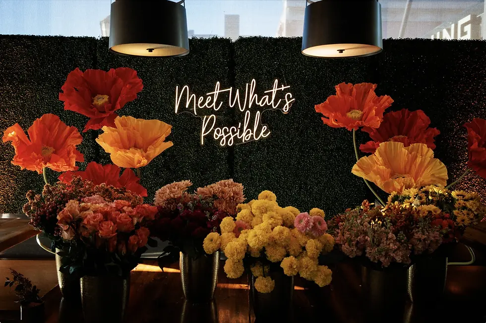 'Meet What’s Possible' sign on a floral roadshow display.