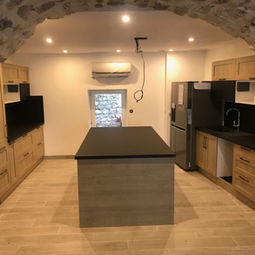 Cuisine moderne avec îlot central sous voûte en pierre apparente rénovée à Nîmes