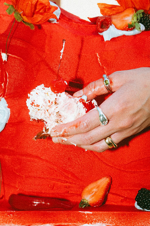 ruka se zlatými a stříbrnými prsteny v organickém designu bere kus dortu