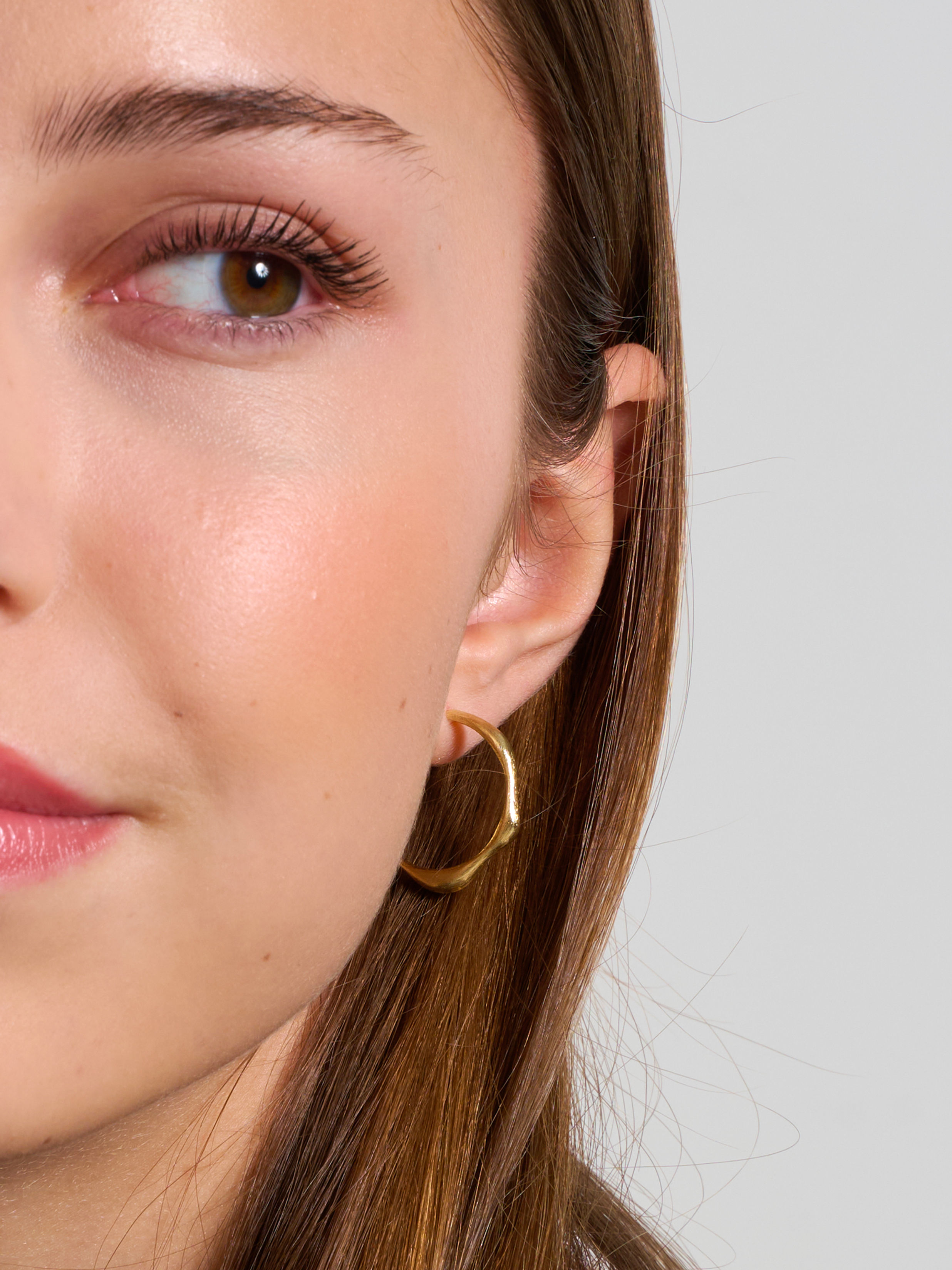 zlaté kruhové náušnice s nepravidelným tvarem od Márie Kobelové na modelce