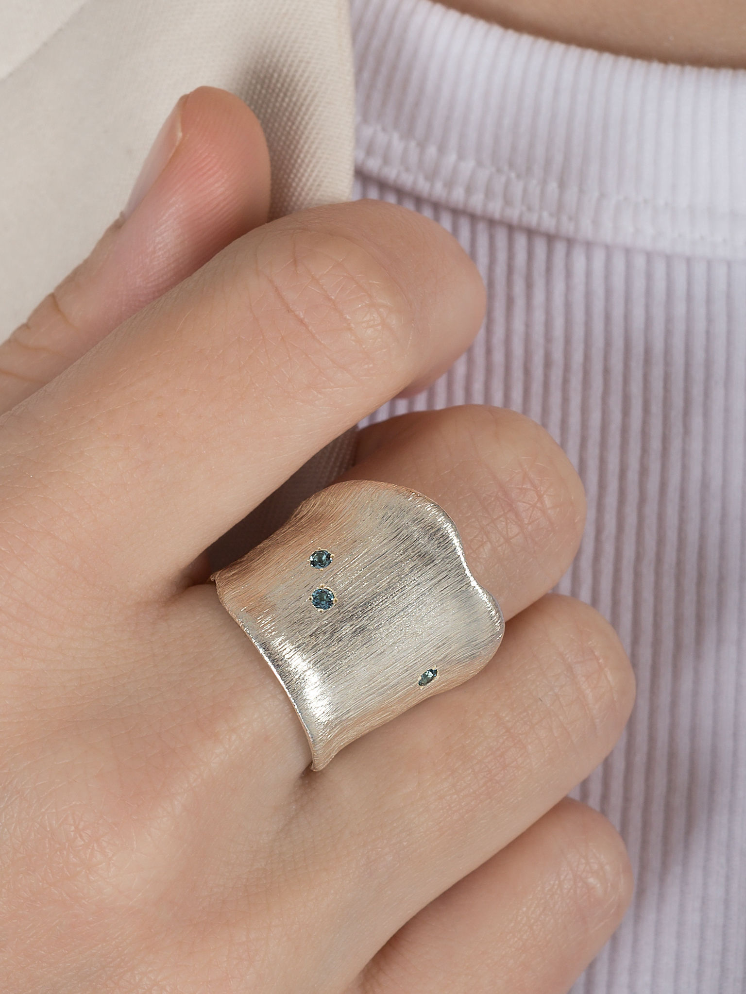 Netradiční moderní stříbrný prsten s modrými topazy na ruce