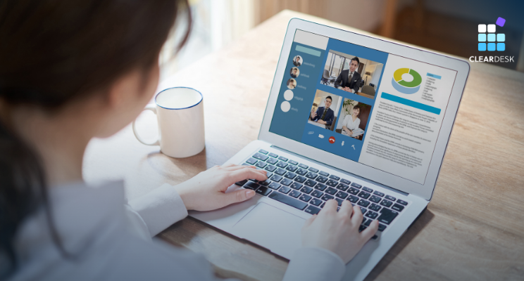 Woman using a laptop for a video meeting with charts and report on screen, ClearDesk logo, coffee mug on desk, focused mood