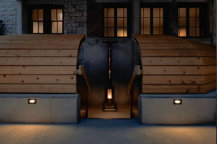 Evening view of the fire pit and outdoor sauna illuminated within the courtyard.