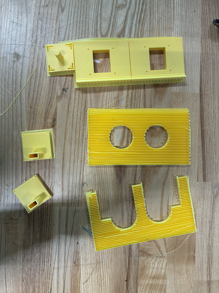Yellow 3D-printed parts on a wooden surface.