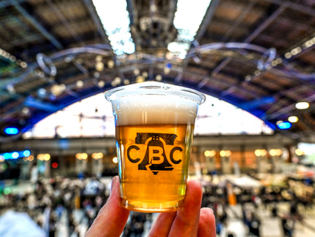 Sample cup of beer with Craft Brewers Conference in the background