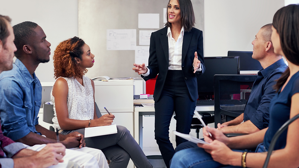 A lady speaking infront of a group of people in a professional setting