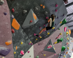 A young girl takes on the climbing wall with determination and focus, showcasing her strength and co