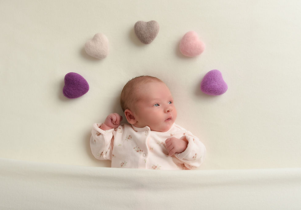 Close-up view of a baby girl with a rainbow of hearts above her head