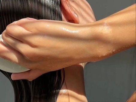 Woman washing her hair at home with shiny, healthy results, showing the importance of daily scalp and hair care habits