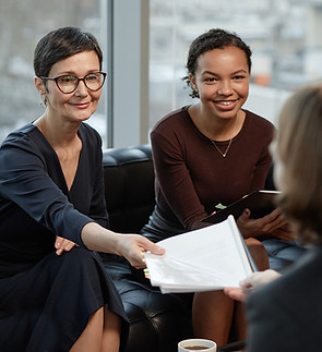 Two smiling females working and handing papers