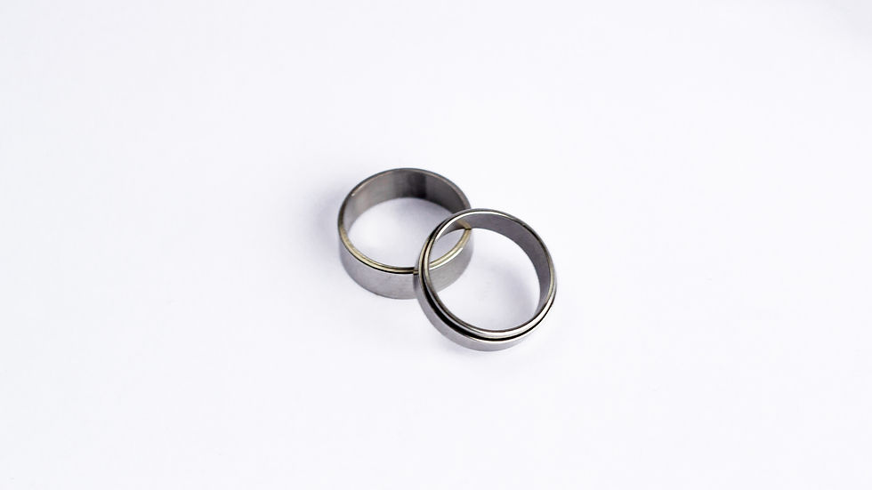 Two titanium rings overlap on a plain white background, creating a minimalist and elegant scene.