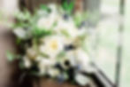 Bouquet of white flowers with green leaves and blue thistle, placed on a windowsill. Natural light creates a serene and fresh mood.