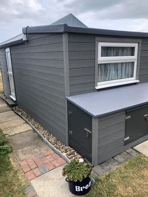 Grey composite cladding and GRP fiberglass roofing on a beach hut in Dorset for durable coastal weather protection.