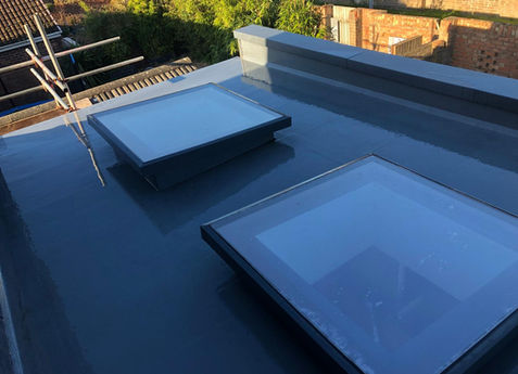 New grey GRP fibreglass flat roof installation featuring two large modern skylights on a Dorset property extension.