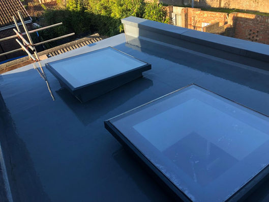 New grey GRP fibreglass flat roof installation featuring two large modern skylights on a Dorset property extension.