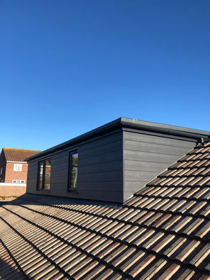 Dark grey dormer extension featuring composite cladding, GRP roofing, and matching uPVC guttering in Dorset.