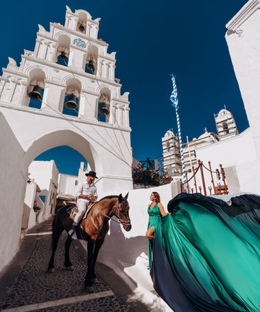 Woman in flying dress posing with horse in Megalochori Santorini