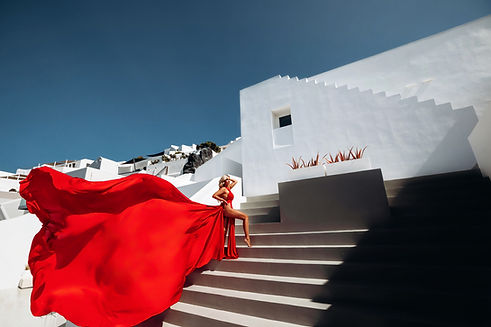 girl in iconic red flying dress in Saint hotel in Santorini