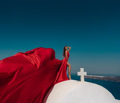 Luxury fashion portrait with flying dress in Santorini