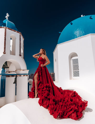 women in red cloud dress in Oia near blue domes 