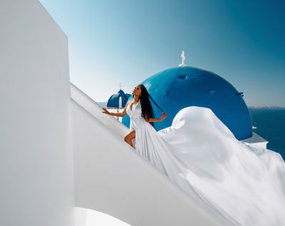 Solo flying dress photoshoot in Santorini with blue dome background
