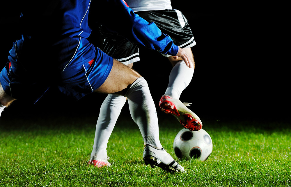 Soccer players compete for the ball.