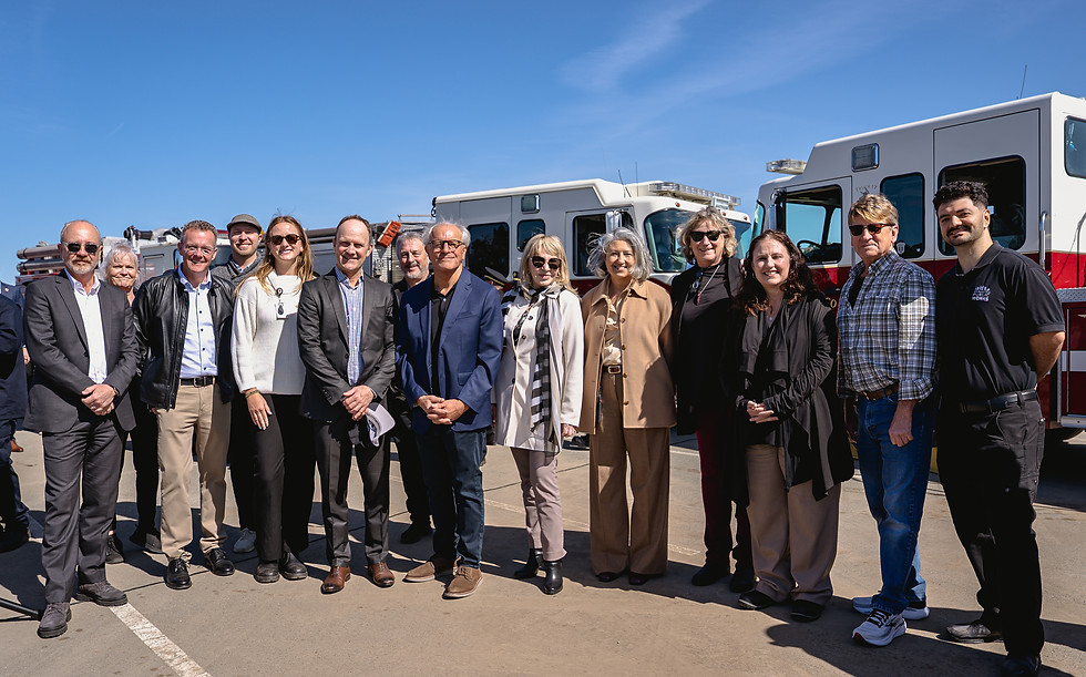 The San Francisco Public Works team for the San Francisco Fire Department Division of Training project poses for a photo in front of some fire trucks.