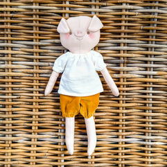 An heirloom pig doll dressed in a raglan top and velvet shorts.
