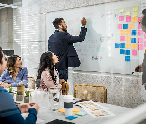 Gifits team collaborating in a business meeting, discussing transformation strategies on a whiteboard. This represents the process of creating customized business transformation plans, focusing on key strategic frameworks of processes, data, technology, experience, and culture.