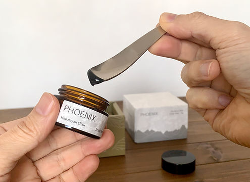 Scooping PHOENIX Shilajit resin from the jar using a small stirrer