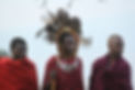Three Maasai men in traditional red clothing and headdresses