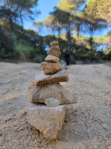 Aufgestapelter Steinturm auf einem Sandweg im Wald als Symbol für innere Balance und den Weg zu sich selbst