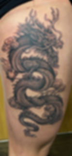 Intricate dragon tattoo with scales and clouds on skin