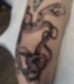 Black ink snake tattoo with open mouth and fangs.