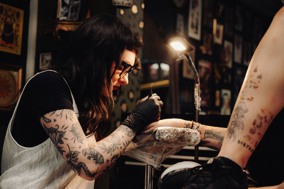 Megan, handpoke tattoo artist tattooing a client's arm in a tattoo studio, milton keynes.