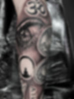 Arm tattoo with Om symbol, eye, and Buddha silhouette.