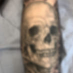Detailed black and grey skull tattoo on an arm.