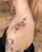 Small handpoke ornamental black ink tattoo on the top of a shoulder