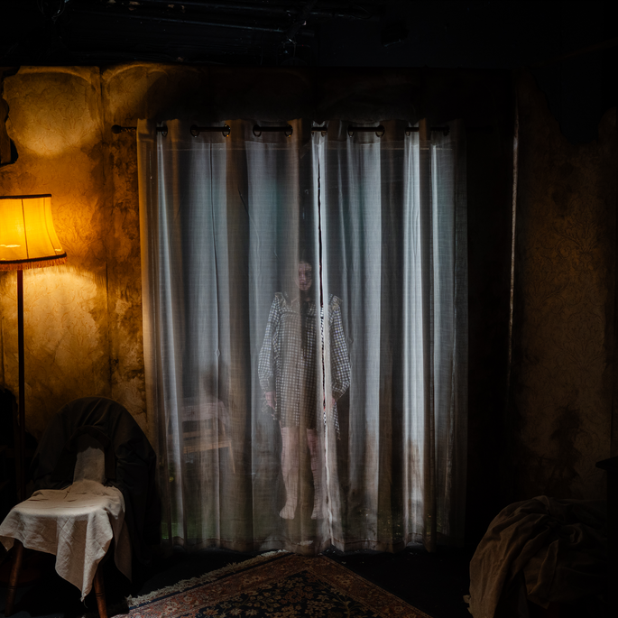 A ghostly figure behind curtains