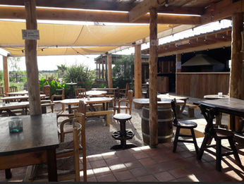 Terrasse de la Taverne du Pirate AcroVertige, avec tables et chaises, ambiance ensoleillée, en plein air.