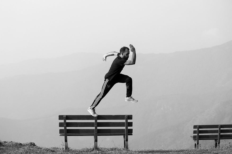 A man runs on top of a park bench
