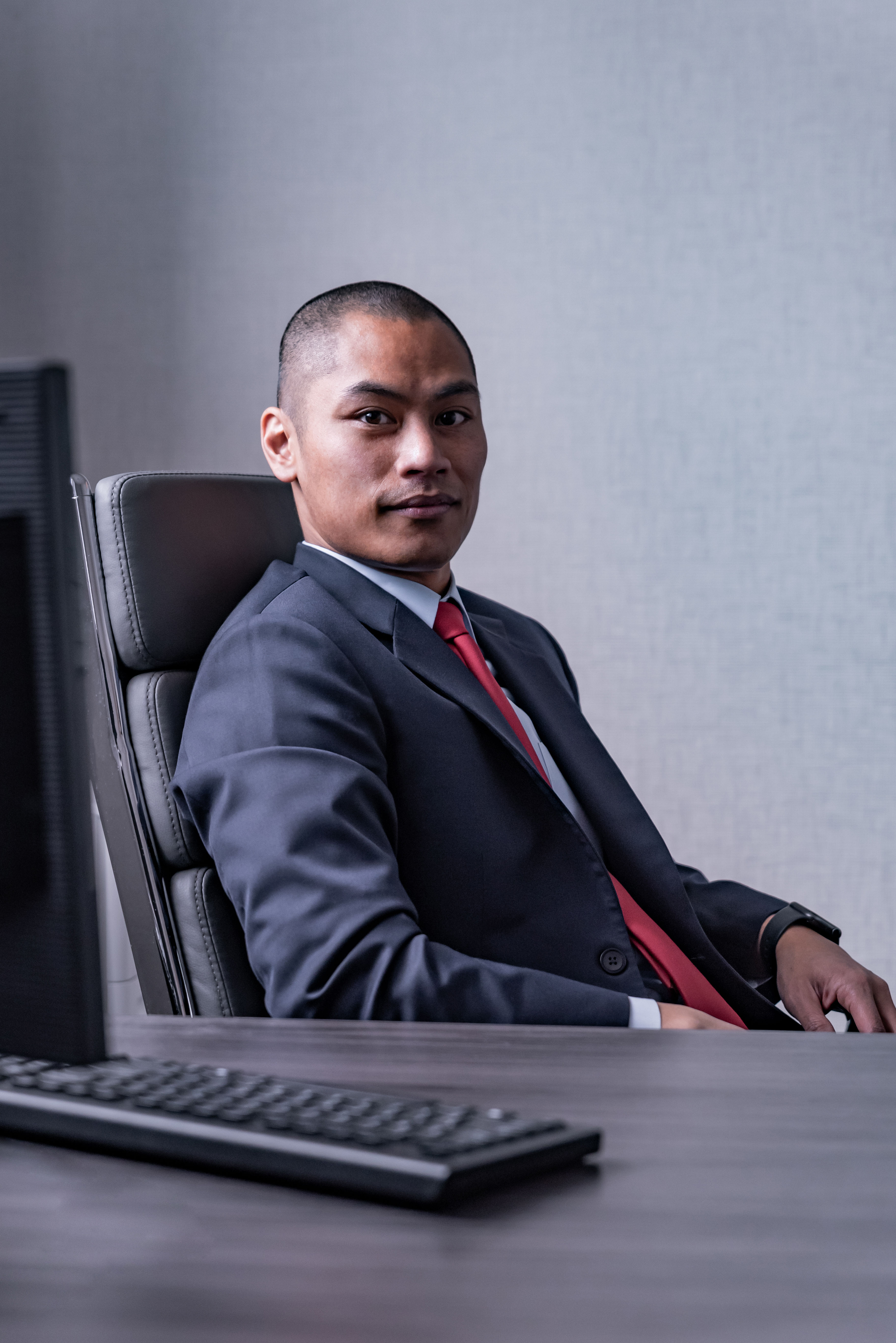 Rob Taclan sitting at a desk in a suit