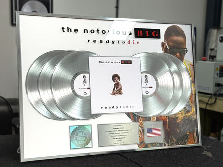 Custom multi-platinum Ready to Die plaque award featuring six silver vinyl records, central album artwork from The Notorious B.I.G.’s Ready to Die, RIAA multi-platinum certification hologram, engraved presentation plate, and USA flag detail in a luxury framed display. Bespoke music industry award created by Plaque Awards Ltd.