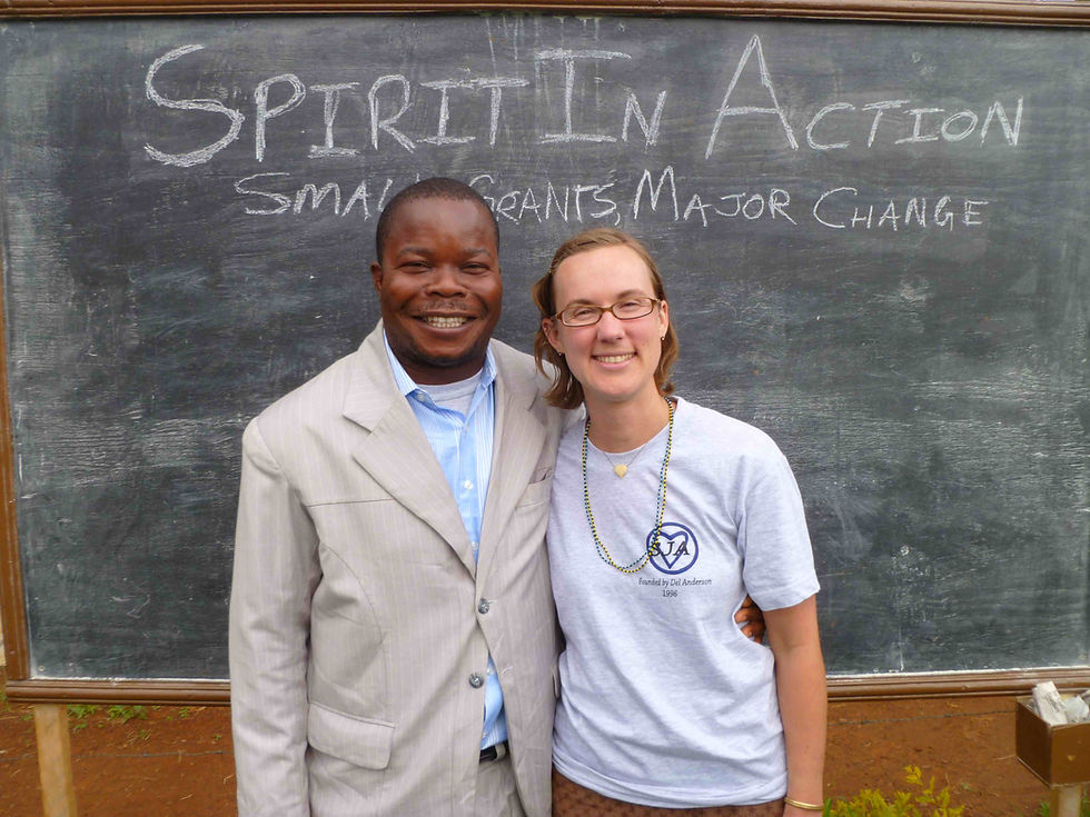 a black man and white woman smiling and standing in front of a blackboard that says Spirit in Action.