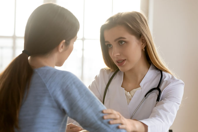 Supportive young female doctor in white medical uniform touch patient arm show empathy and