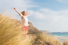 Relaxed woman, arms rised, enjoying sun, freedom and life an a beautiful beach. Young lady