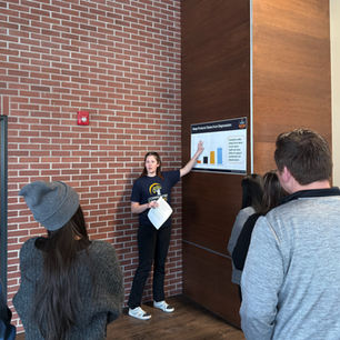 C4Y staff member presents a poster on "Sleep Protects Teens from Depression" to a group of people in a brick-walled room. Attendees listen attentively.