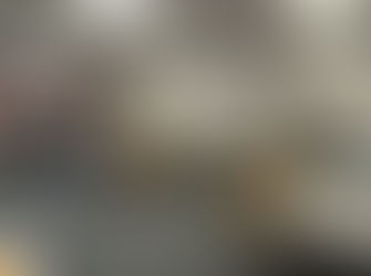 People in a classroom stand by walls discussing posters taped to the walls. Tables and chairs fill the room.